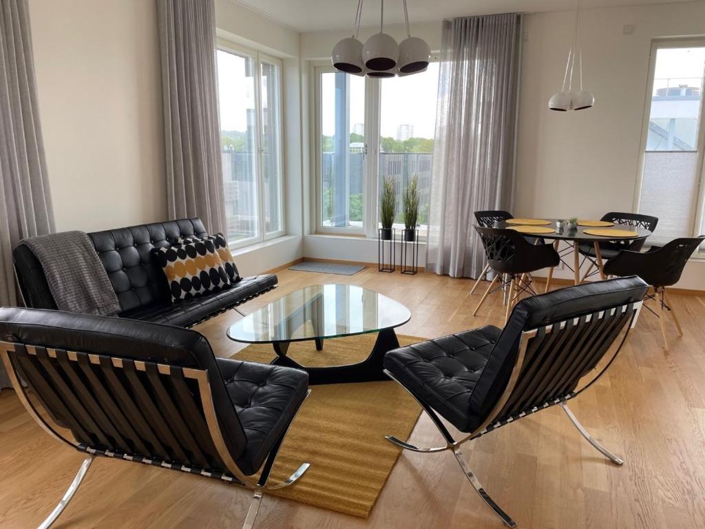 a living room with black furniture and a glass table at Penthouse Kadriorg in Tallinn