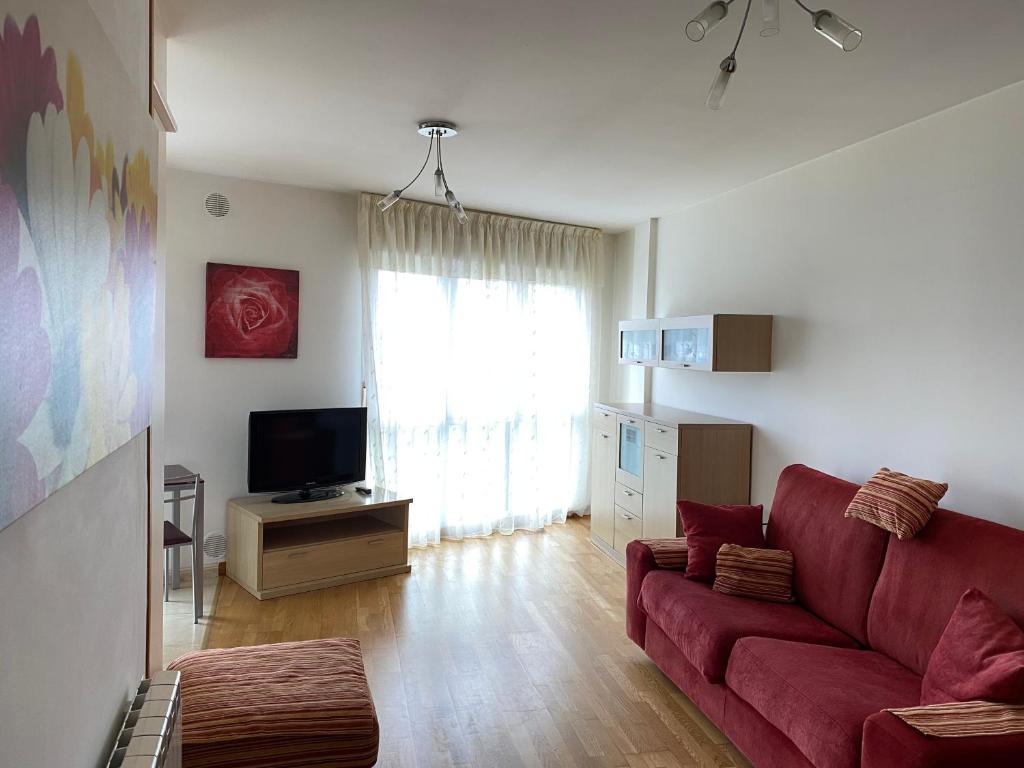 a living room with a red couch and a television at Edificio Mora in Boiro