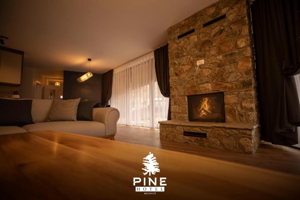 a living room with a stone fireplace and a couch at Pine Villas Brezovice in Brezovicë