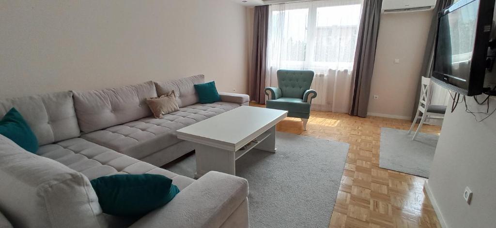 ein Wohnzimmer mit einem Sofa und einem TV in der Unterkunft 2H Apartment in Sarajevo