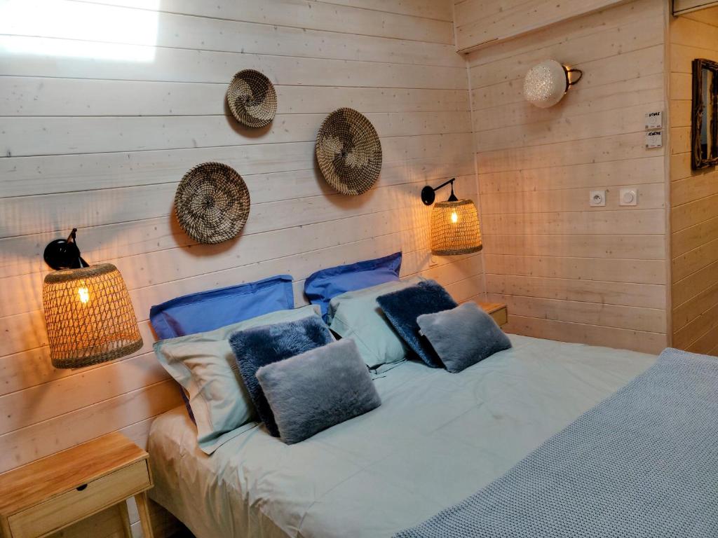 een slaapkamer met een bed met blauwe kussens en 2 verlichting bij La Cabane de Didi in Andernos-les-Bains