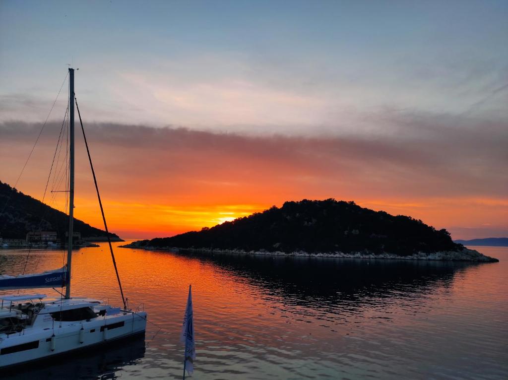 um barco na água ao pôr do sol com uma ilha em Apartmani Kate em Lastovo