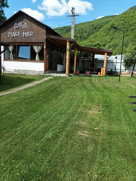 a barn with a grass field in front of it at Casa Mary Mar in Tîrgu Ocna