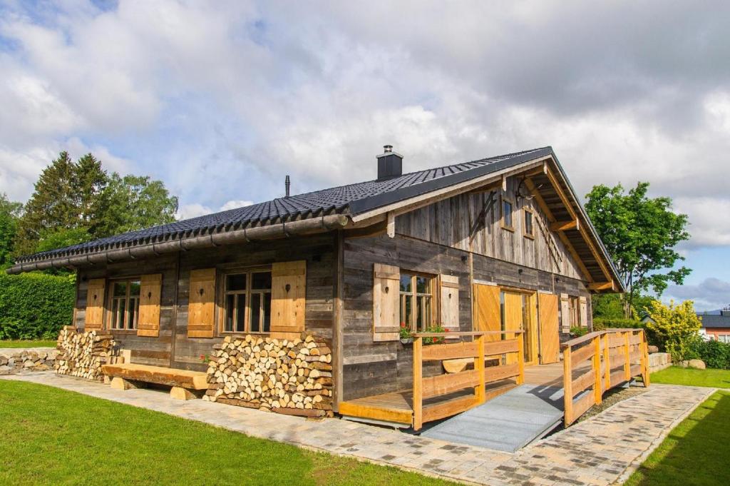 ein großes Holzhaus mit einem Stapel Holz in der Unterkunft Chalet am Ölberg mit Badefass und Altholzsauna in Waldmünchen