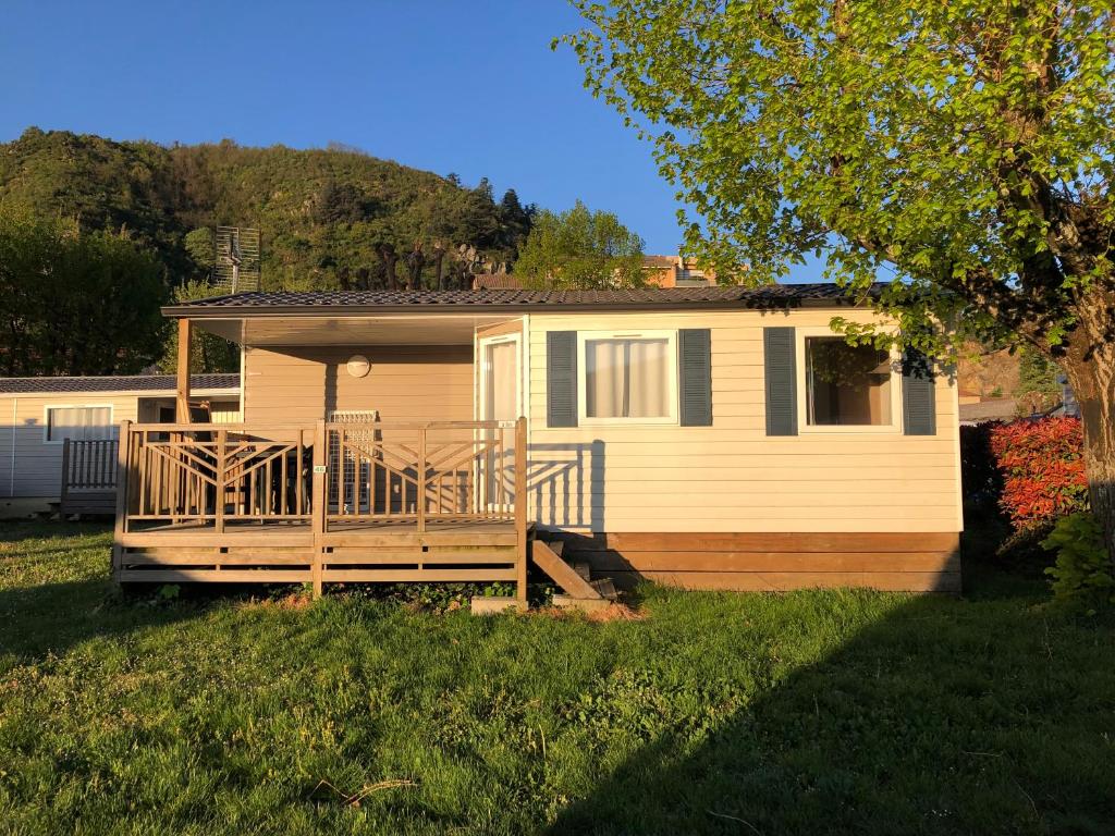 a home with a large wooden deck on a yard at Camping le Rhône in Tournon-sur-Rhône