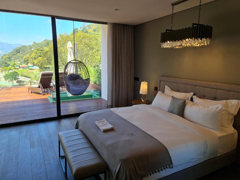 a bedroom with a bed and a large window with a swing at Douro Suites in Riba Douro