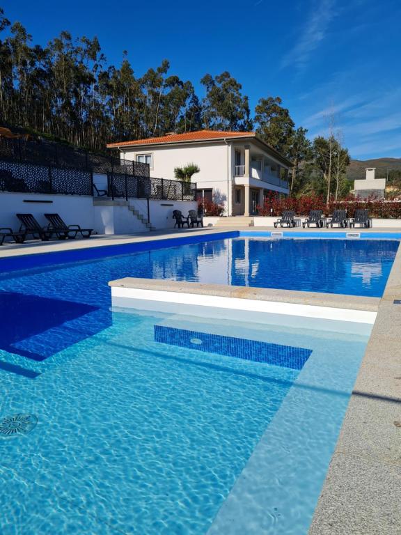 una piscina de agua azul frente a una casa en Paraiso Do Gabriel 