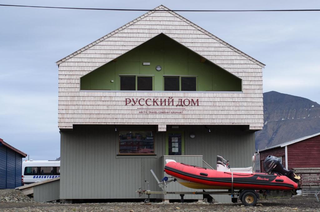 a red boat is parked outside of a building at Russkiy Dom in Longyearbyen