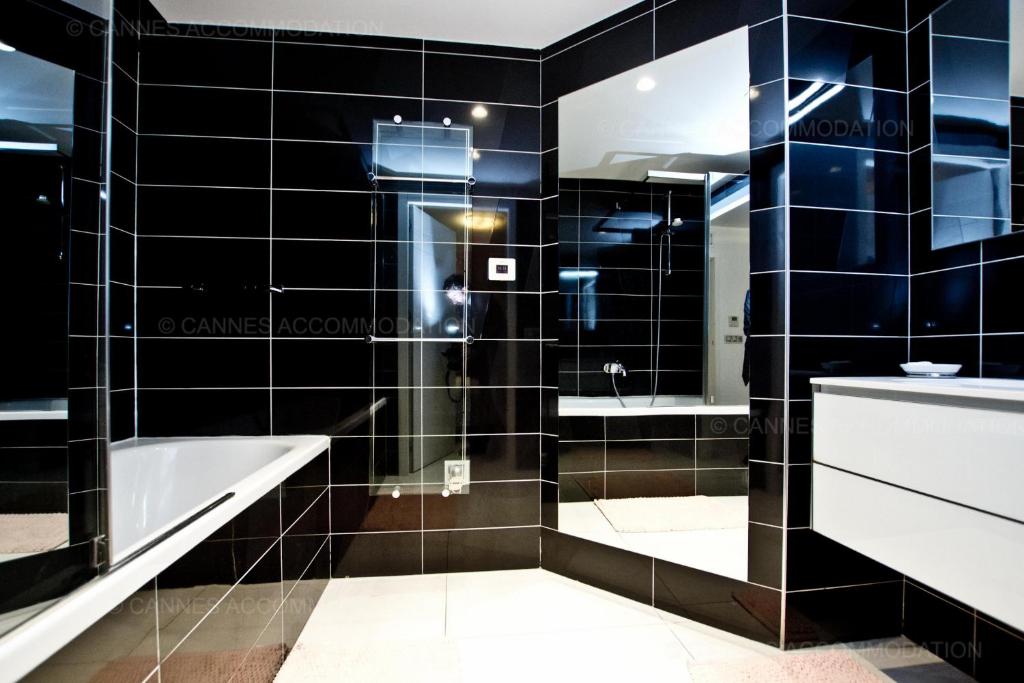 a black tiled bathroom with a tub and a sink at 7 Croisette 7C201 in Cannes