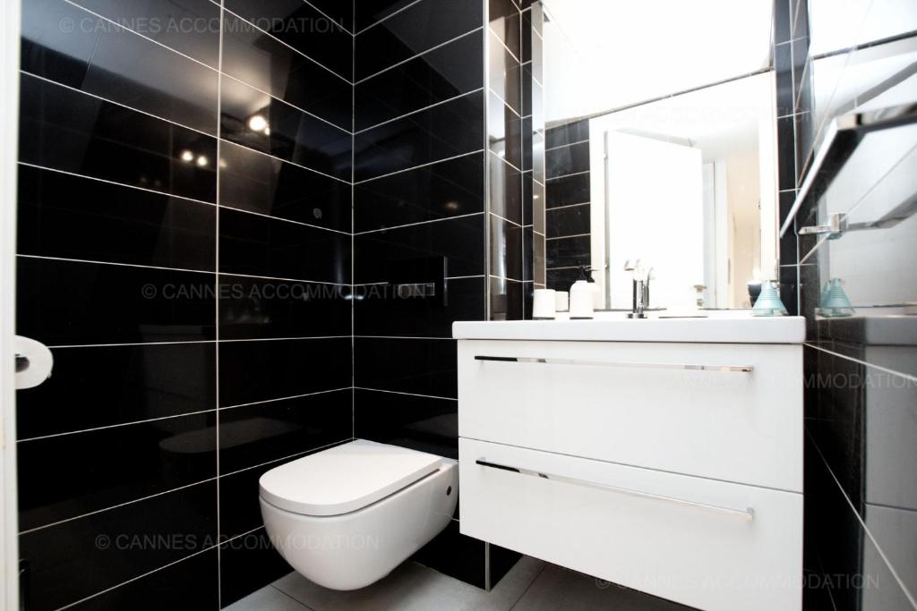 a black tiled bathroom with a white toilet and a sink at 7 Croisette 7C201 in Cannes