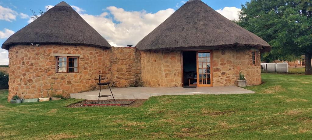 a small stone building with two thatched roofs at Blackbrook Farm Underberg in Underberg