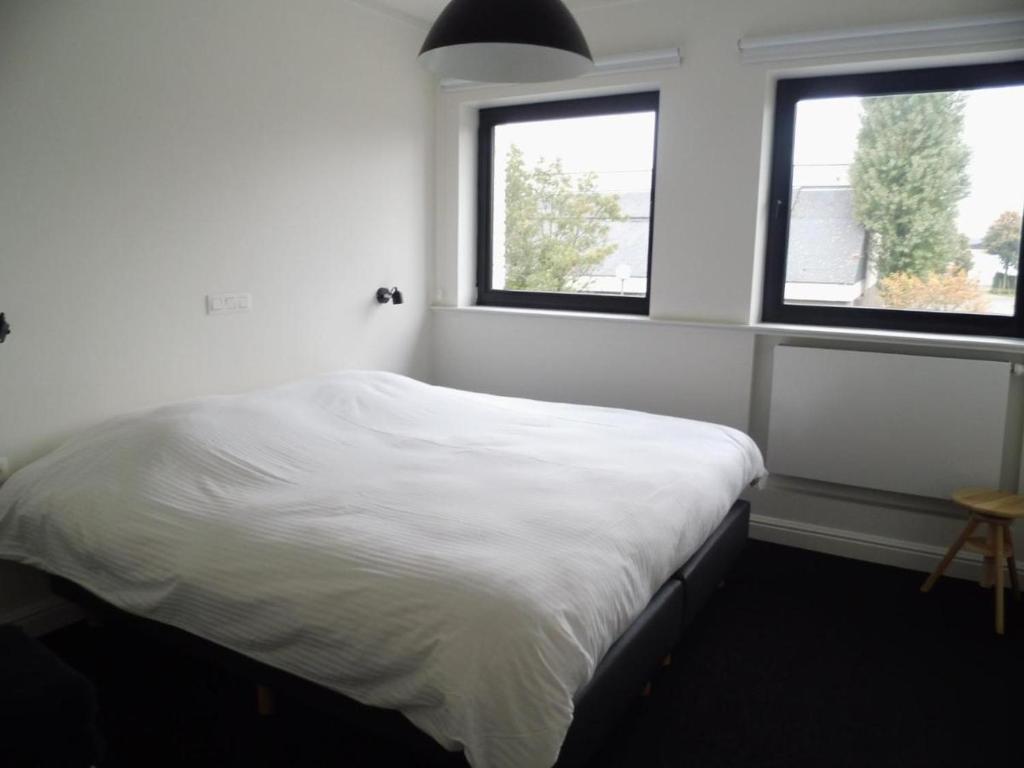 a bedroom with a white bed with two windows at Quarante Cinq in Evergem