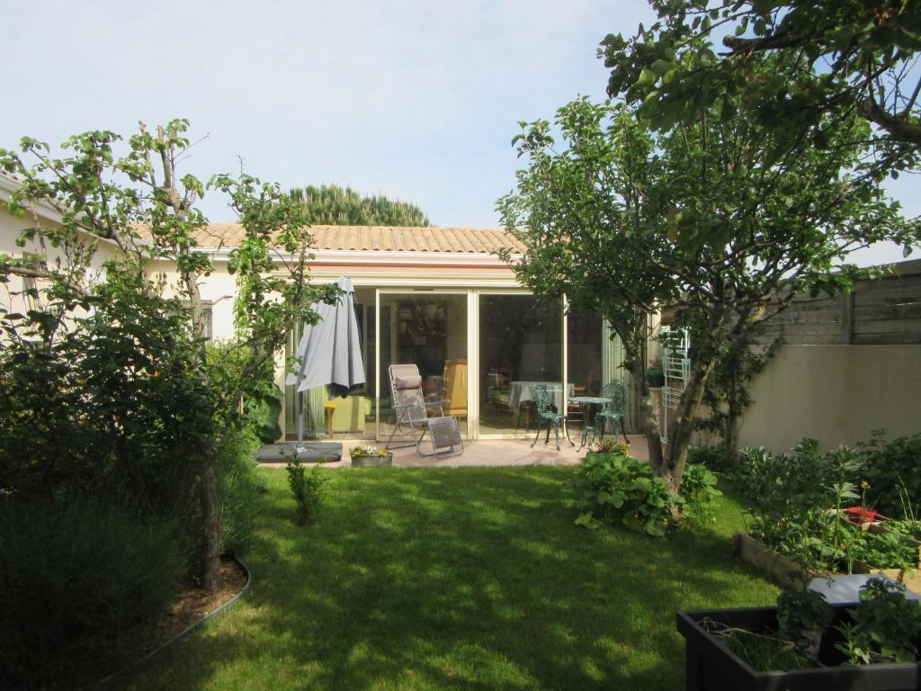 een achtertuin met een patio en een tuin met groen gras bij Pied à Mer et Nature in Lagord