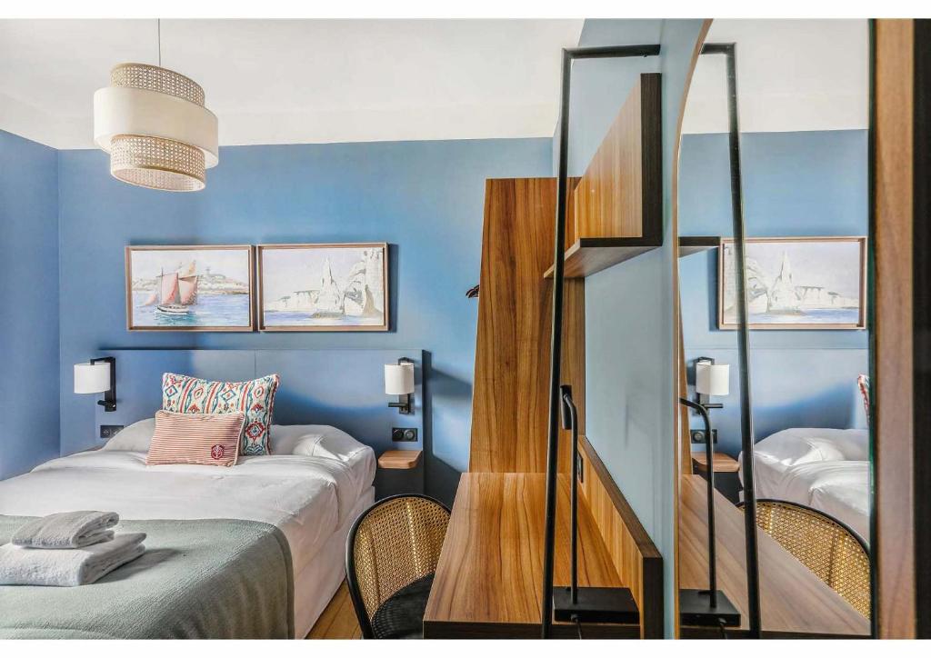 - une chambre avec des murs bleus, un lit et un miroir dans l'établissement Hôtel Restaurant Le Cap, à Barneville-Carteret