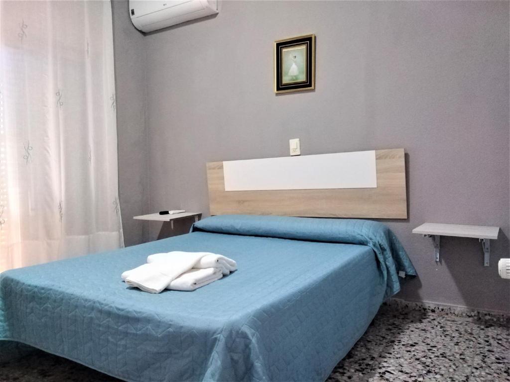 1 dormitorio con 1 cama azul y 2 toallas en Habitaciones de Hostal a Primera linea de playa en Cullera, en Cullera