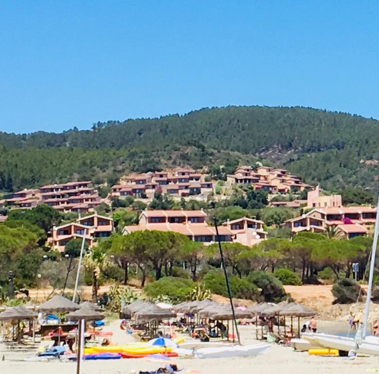 un gruppo di persone su una spiaggia con edifici di Casa Vacanza Porto Corallo a Villaputzu