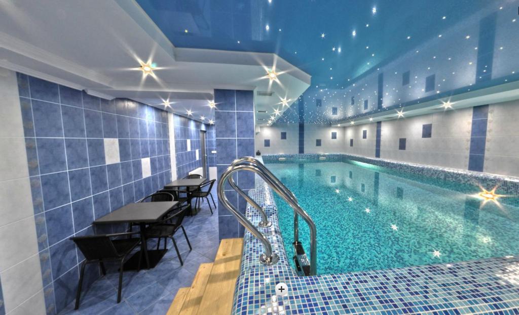 ヤシニャにあるHotel Forward Pool&Saunaのテーブルと椅子付きのホテル内のプールを利用できます。