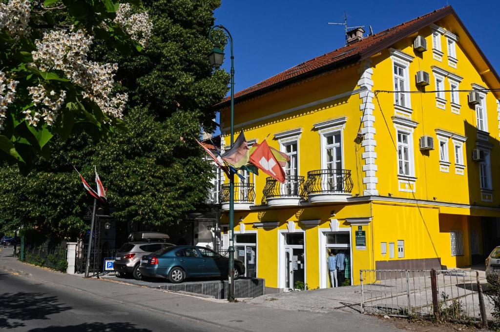 a yellow building with cars parked in front of it at Ornament Hotel in Sarajevo