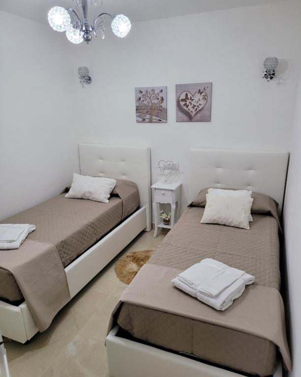 twee bedden in een kamer met witte muren bij La Casa Delle Rose 1 in Giba
