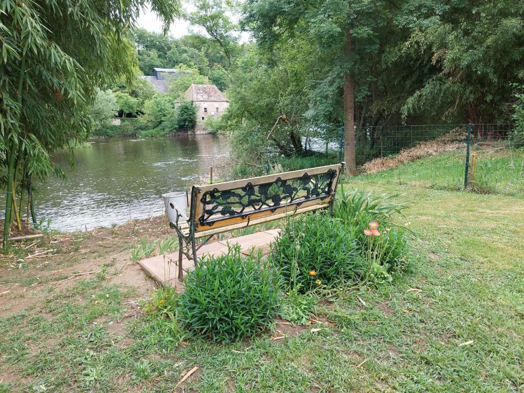 eine Parkbank vor einem Fluss in der Unterkunft Gite 3 étoiles, Maison spacieuse en bord de rivière in Saulgé