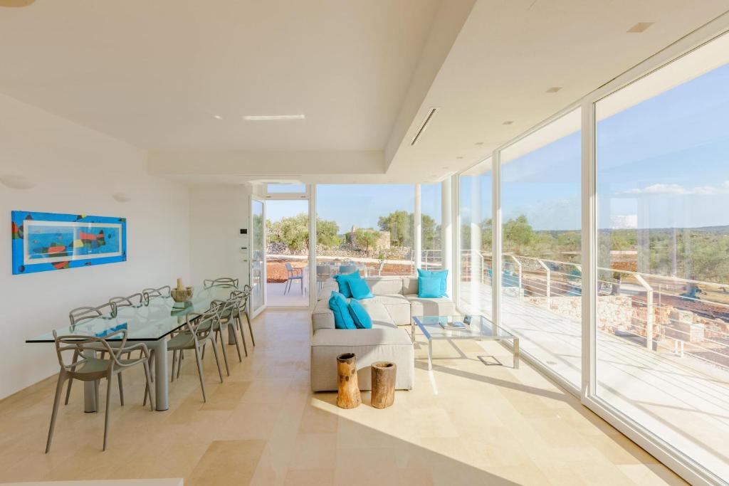 une salle à manger avec une table, des chaises et des fenêtres dans l'établissement Villa Panitria, à Ostuni