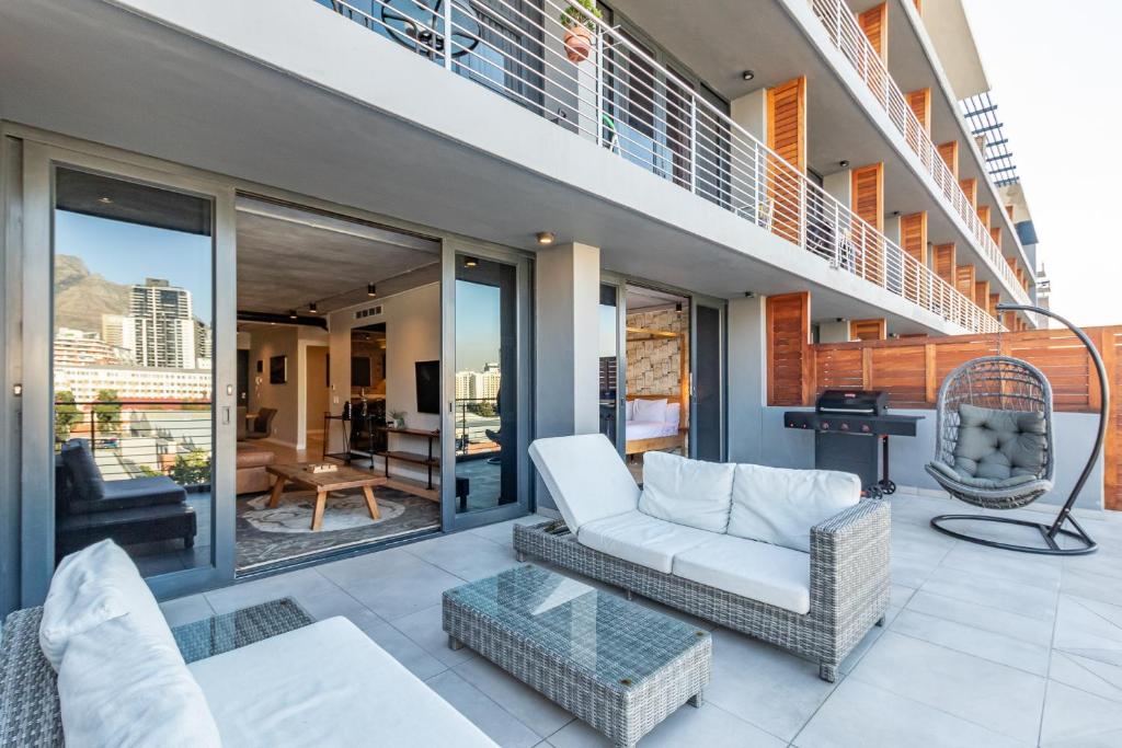 uma sala de estar com um sofá e cadeiras numa varanda em Docklands Luxury Two Bedroom Apartments em Cidade do Cabo