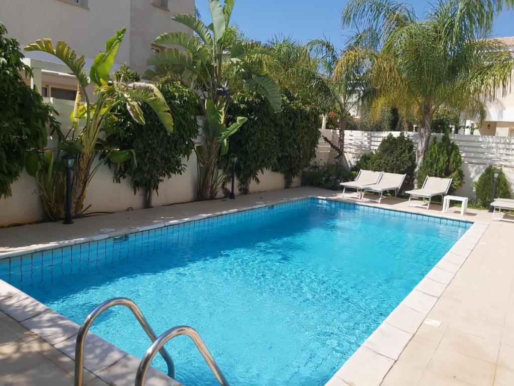 a large swimming pool with chairs next to a building at Anthorina Villa 10 in Protaras