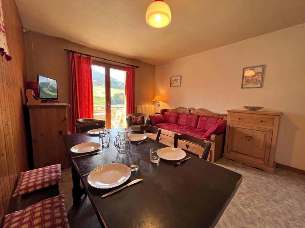 un salon avec une table et un canapé rouge dans l'établissement Crepuscule 3 - Appartement proche pistes de ski et village, à La Clusaz