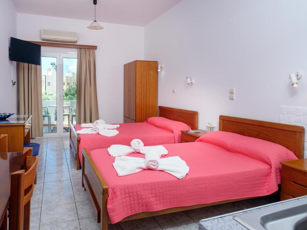 ケラトカンボスにあるStudios Eftihiaの赤いシーツとシンクが備わるベッド3台付きの部屋