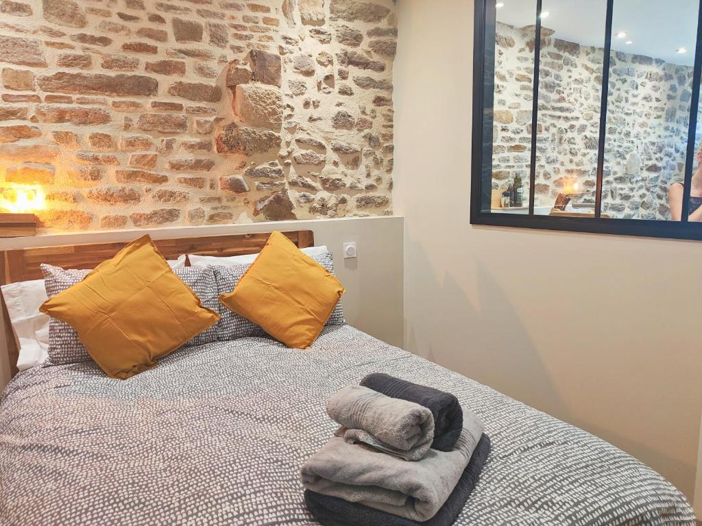 a bedroom with a bed with yellow pillows and a brick wall at Appart Halo et Duplex Les Filles in Dinan