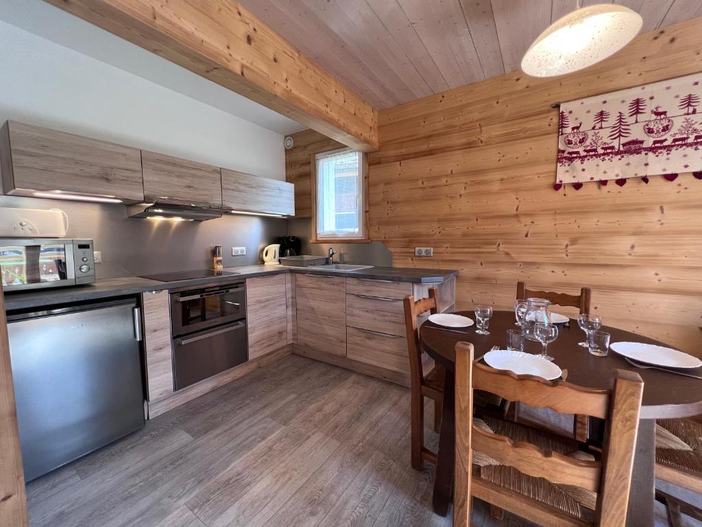 une cuisine avec une table à manger et une cuisine avec des murs en bois dans l'établissement Crepuscule 4 - Appartement proche pistes de ski et village, à La Clusaz