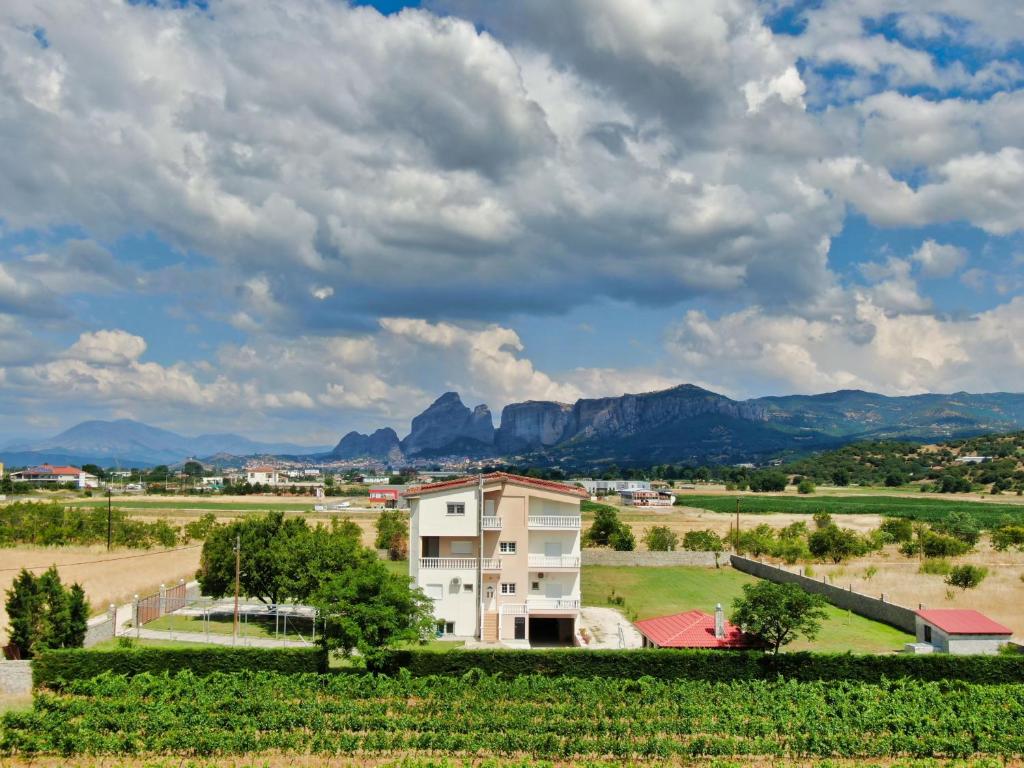 ein Haus auf einem Feld mit Bergen im Hintergrund in der Unterkunft Spilaio at Meteora in Kalambaka