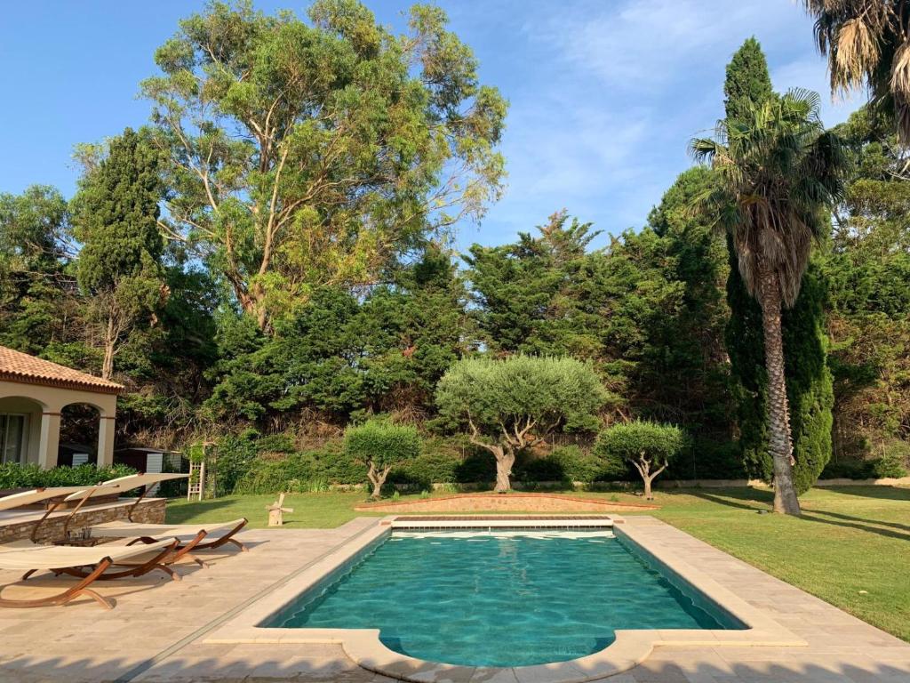 Claira的住宿－maison d'hôtes 2 personnes les deux esprits libres，一个带长椅和树木的庭院内的游泳池