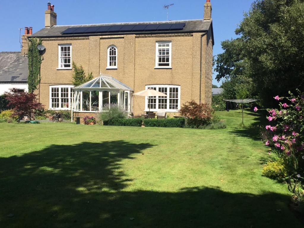 a large brick house with a lawn in front of it at The Oaks in Swaffham