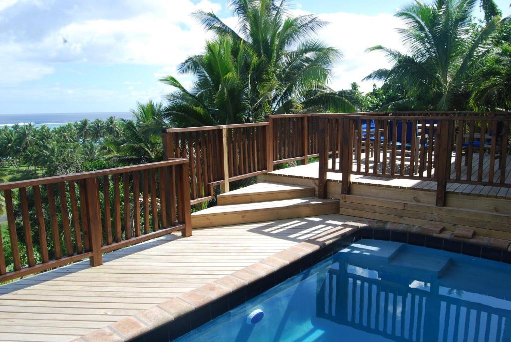 una terraza de madera con piscina y el océano en Moana Villa Aitutaki en Arutanga