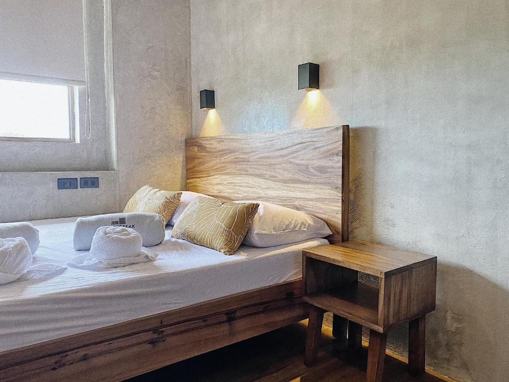 a bed with a wooden head board and a table at Shorebreak Hostel San Juan La Union in san juan la union