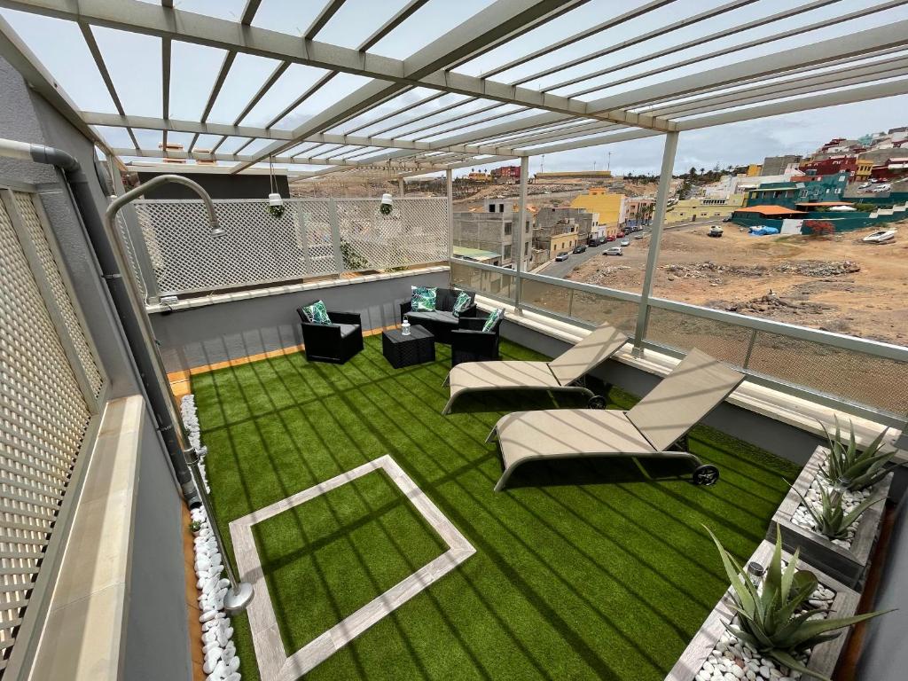 un patio esterno con sedie ed erba su un balcone di ÁTICO "TURQUESA BEACH" CON PISCINA, TERRAZA y BARBACOA a Sardina