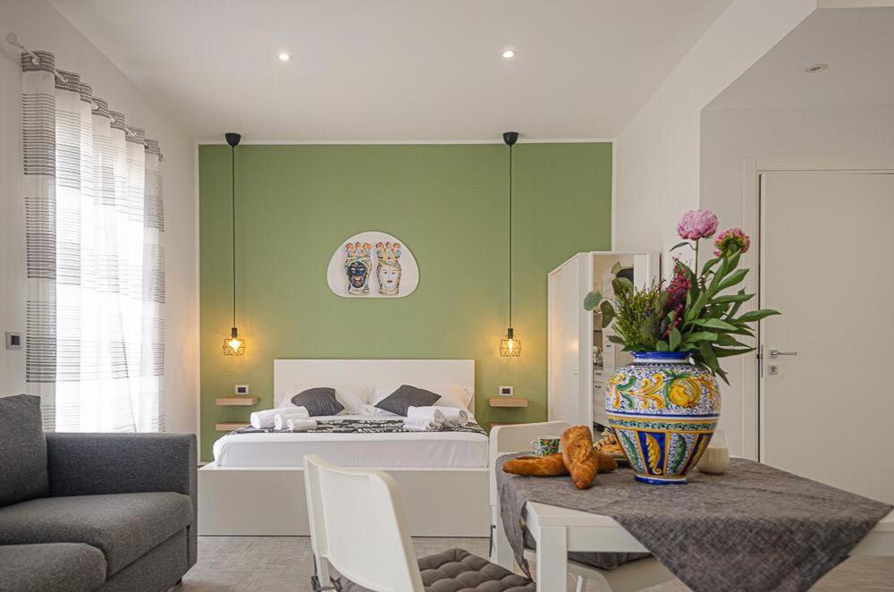 Sunrise Luxury Apartments في كاسيبيلي: غرفة بسرير وطاولة مع مزهرية