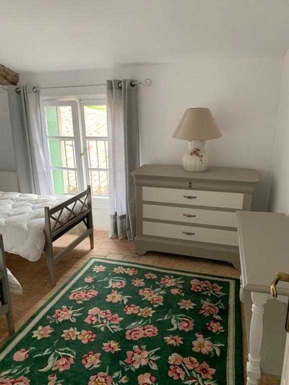 a bedroom with a bed and a dresser and a green rug at La Maison de Leontine in La Livinière