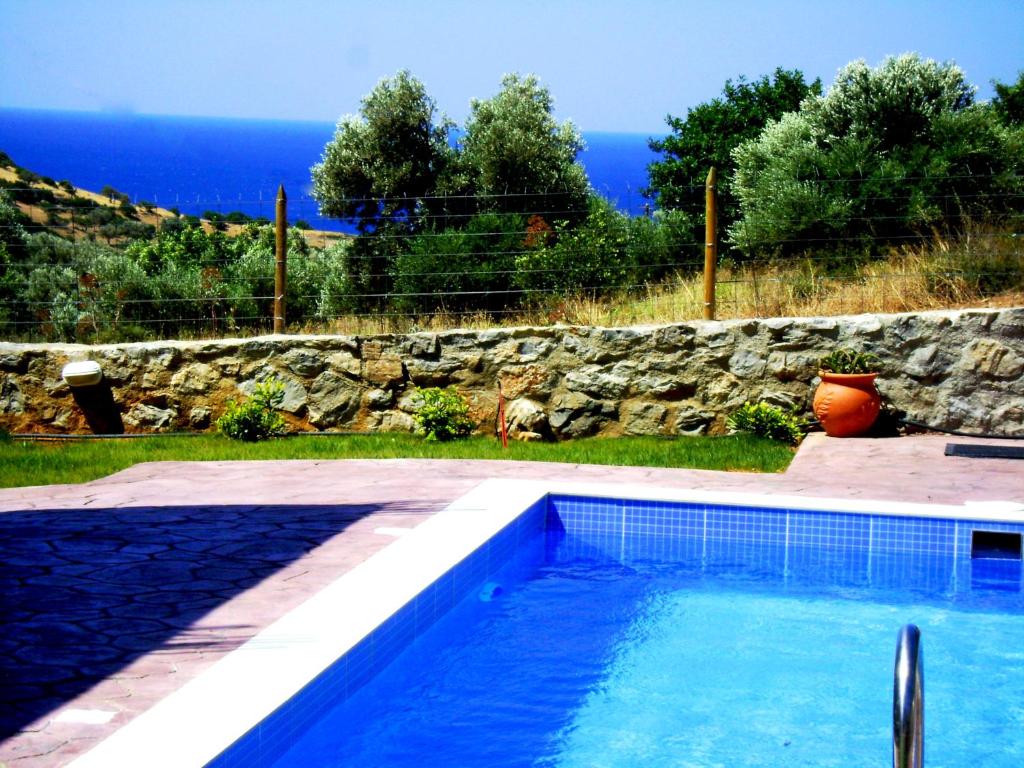 a swimming pool in front of a stone wall at Villa Alexander 2 in Triopetra