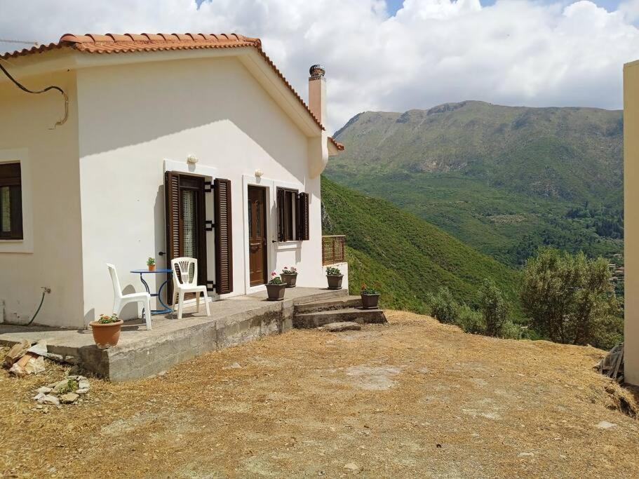 a white house with a table and chairs on a hill at Galini Home: Cozy Home with great view of Taygetos 