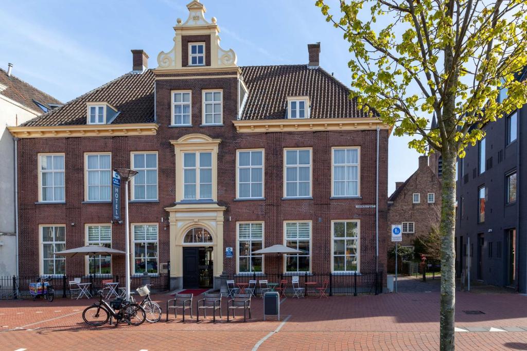 een groot bakstenen gebouw met tafels en stoelen ervoor bij Grand Museum Hotel, BW Signature Collection in Delft