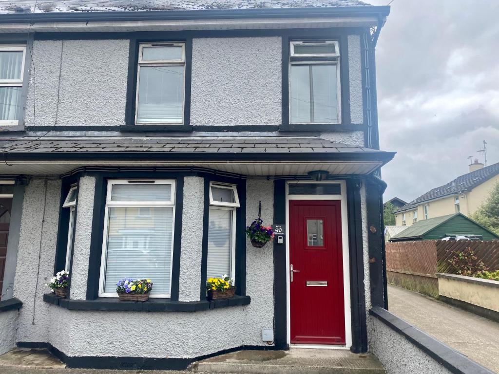 a house with a red door and two windows at An Lar in Bellaghy