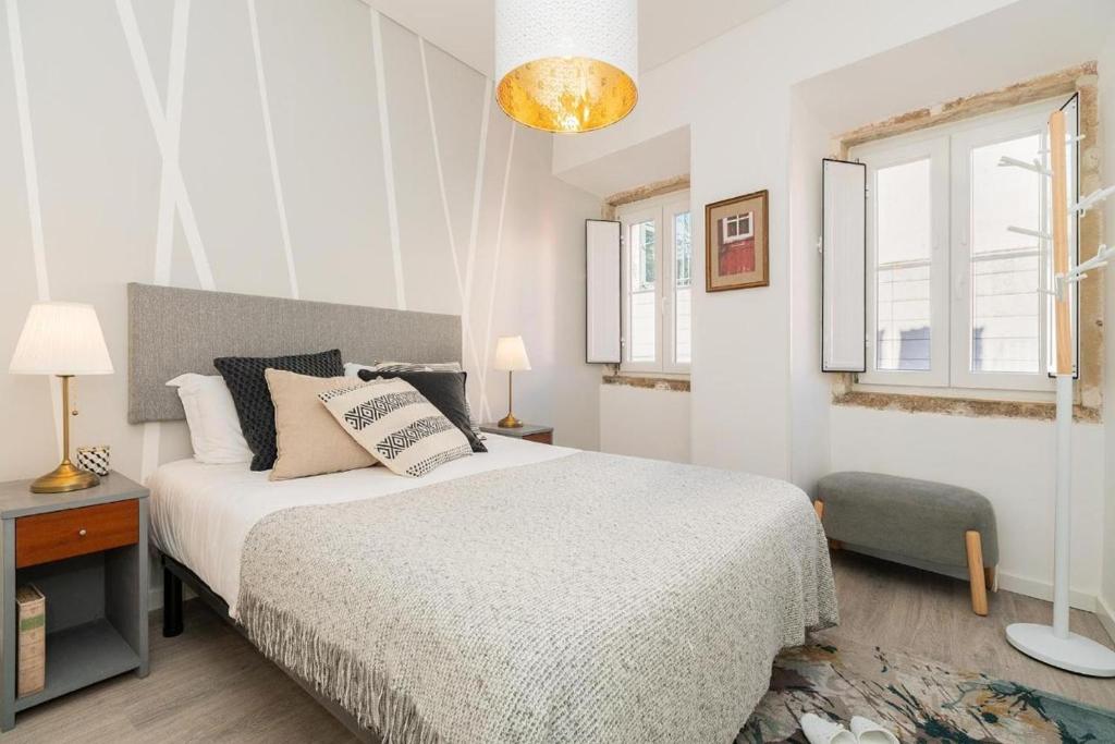 a white bedroom with a bed and a window at Designer Flats in Lapa by LovelyStay in Lisbon