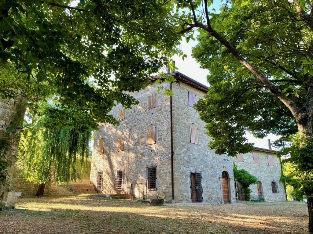un antiguo edificio de piedra con árboles delante de él en Sambuco di Sopra en Fratticciola Selvatica