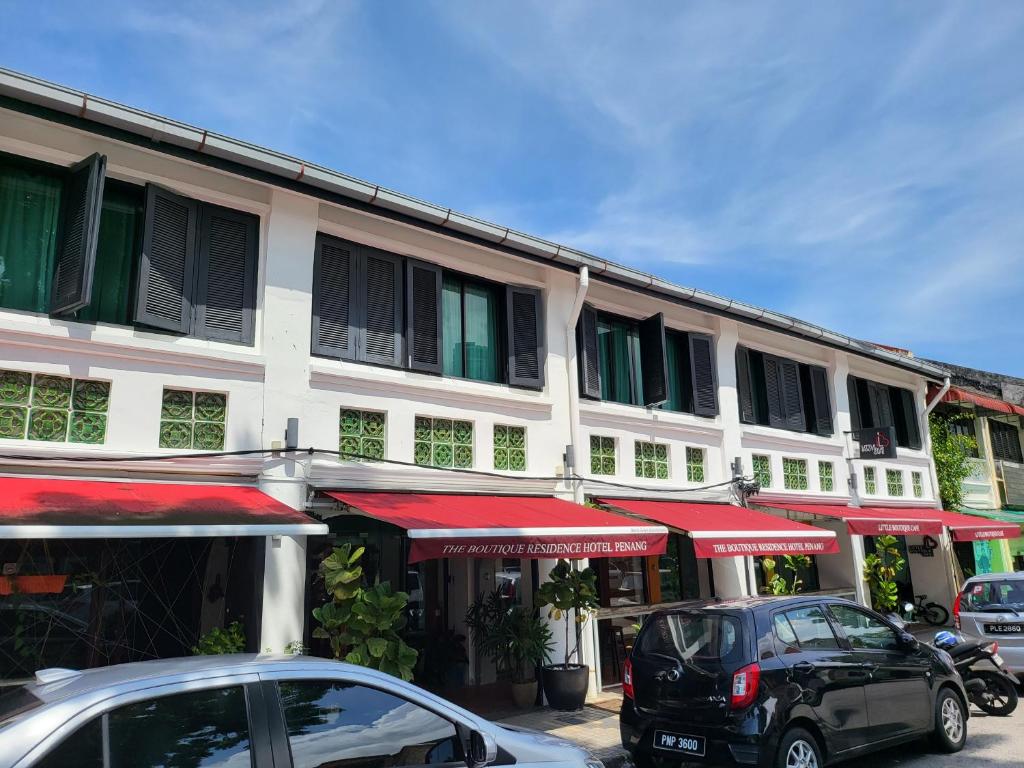 two cars parked in front of a building with red umbrellas at The Boutique Residence Hotel in George Town