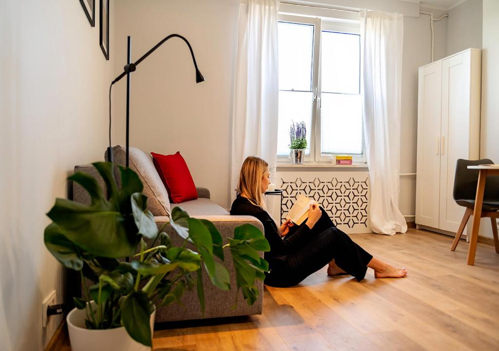 a woman sitting on a couch in a living room at Baltic Breeze Studio Gdynia -stylowe studio 2-os, blisko morza in Gdynia