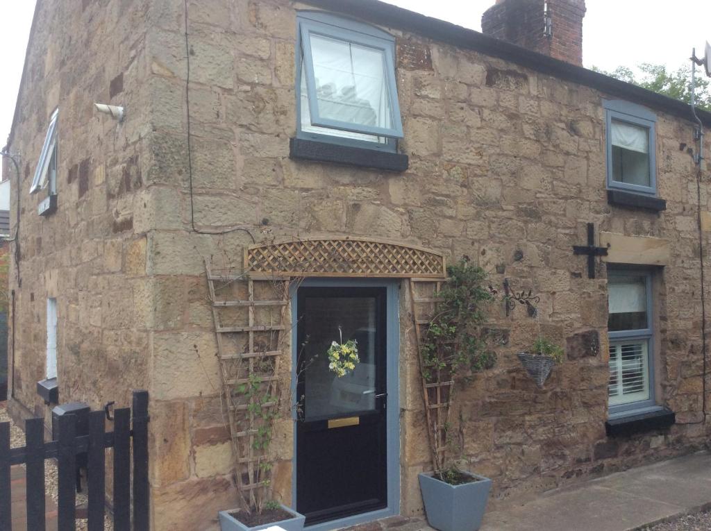 a stone house with a black door and a window at 1850s Character Stone Cottage in Mold