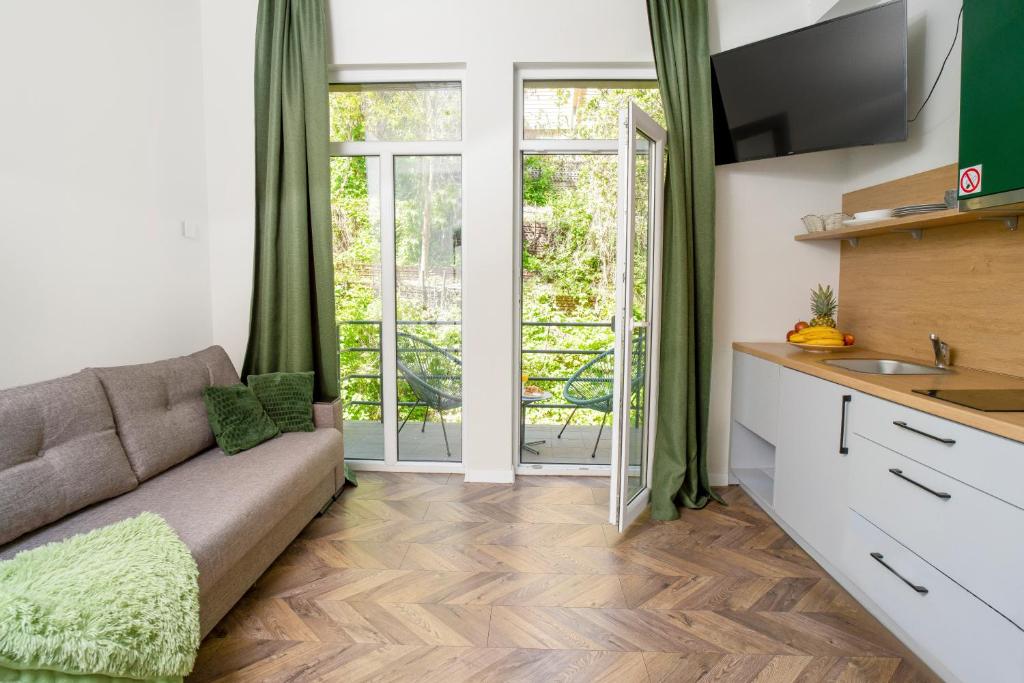 een woonkamer met een bank en een keuken met glazen schuifdeuren bij House 22A Studio Apartments in Kaunas
