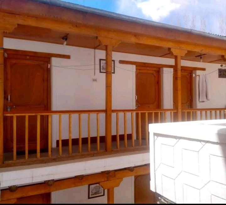 a porch of a house with wooden columns and a balcony at Gomang guest house Leh in Leh